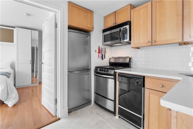 kitchen with stainless steel appliances, light brown cabinets, light tile patterned floors, and decorative backsplash