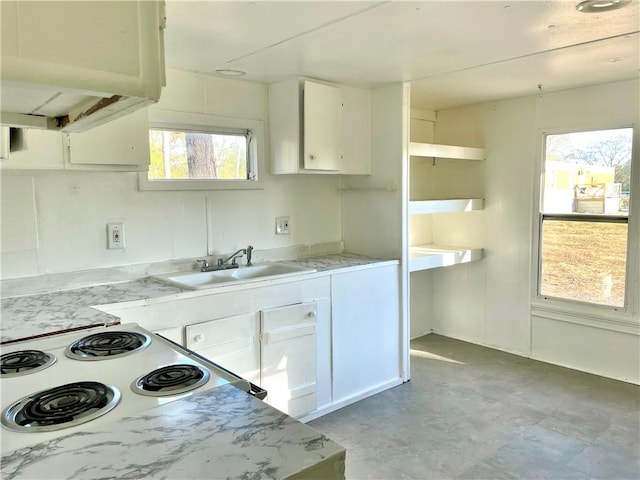 kitchen featuring light stone counters, white range oven, white cabinetry, and sink