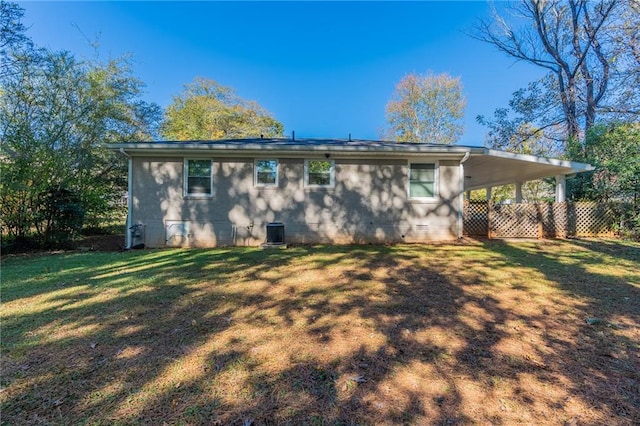 back of house featuring central AC, a yard, and a carport