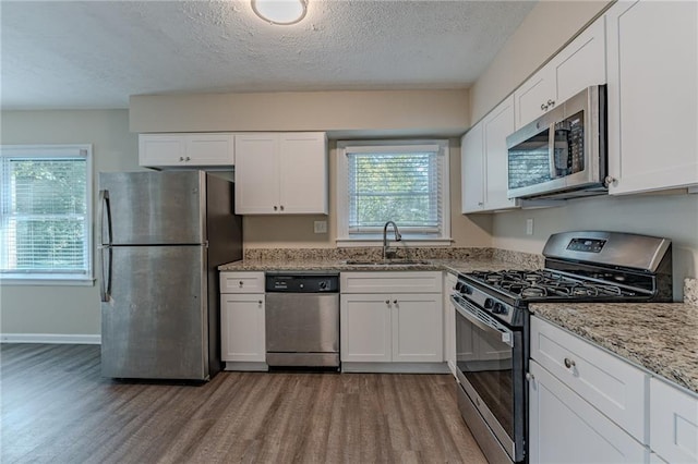 kitchen with white cabinets, light wood-type flooring, stainless steel appliances, and sink