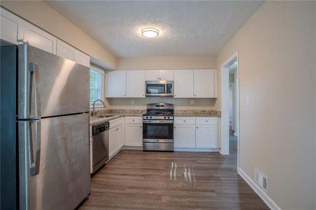 kitchen featuring white cabinets, sink, a textured ceiling, dark hardwood / wood-style flooring, and stainless steel appliances