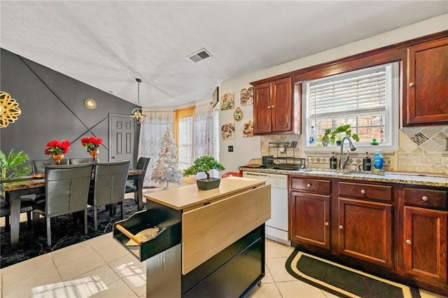 kitchen with white dishwasher, a sink, light tile patterned flooring, light countertops, and vaulted ceiling