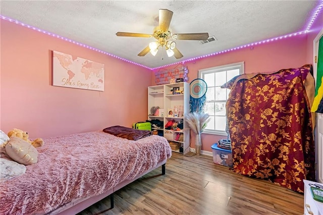 bedroom with wood finished floors, a textured ceiling, and a ceiling fan