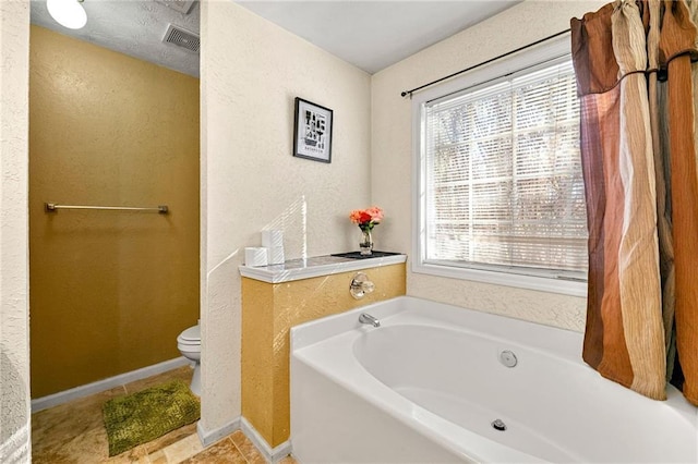 full bath with a garden tub, toilet, and a textured wall