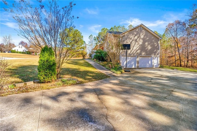 view of side of property with a garage, driveway, and a yard