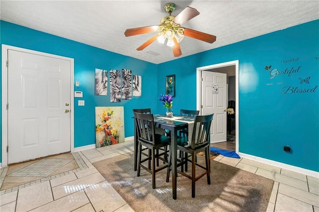 tiled dining space with ceiling fan, baseboards, and a textured ceiling