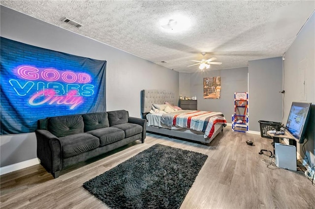 bedroom with wood finished floors, baseboards, a textured ceiling, and ceiling fan