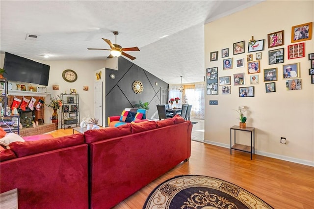living area featuring ceiling fan, wood finished floors, lofted ceiling, and baseboards