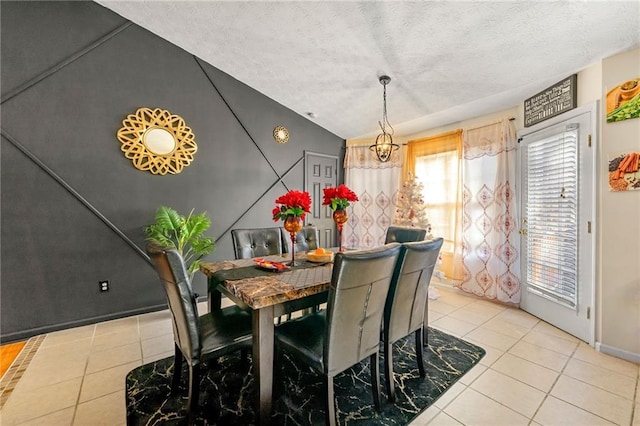 dining area with light tile patterned flooring, a textured ceiling, baseboards, and a chandelier