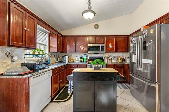 kitchen featuring appliances with stainless steel finishes, lofted ceiling, light tile patterned floors, a center island, and a sink