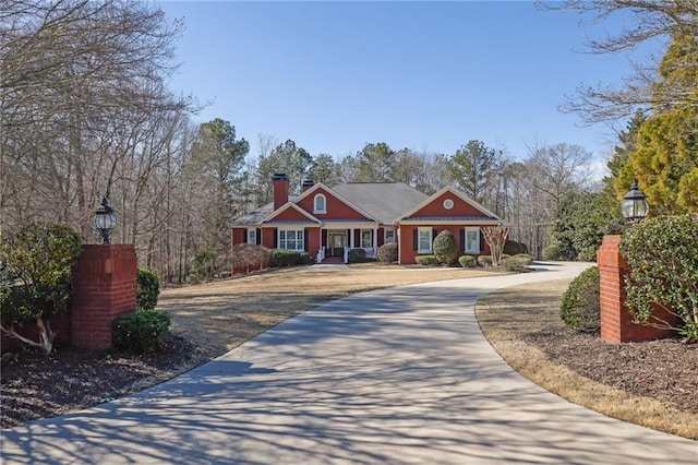 view of front facade with a chimney and driveway