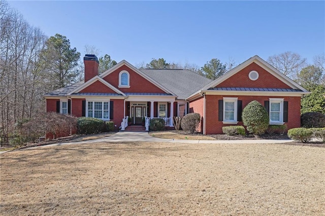 view of front facade with a porch, brick siding, and a chimney