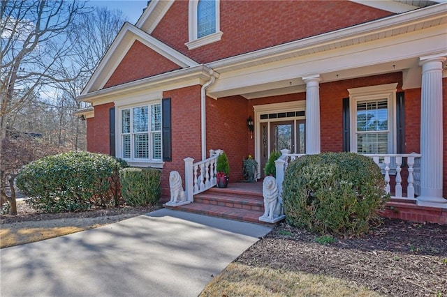 view of exterior entry featuring brick siding and covered porch