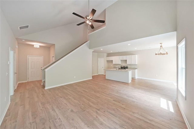 175 W Woods Dr, Dahlonega, GA 30533 - unfurnished living room with high vaulted ceiling, a chandelier, baseboards, light wood-style flooring, and a ceiling fan