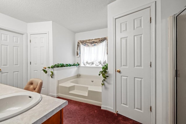 bathroom with a garden tub, a textured ceiling, and vanity