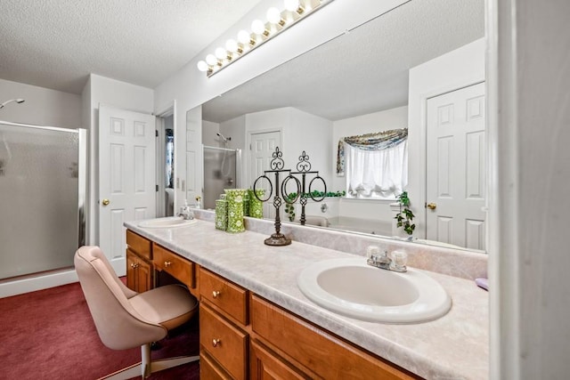 bathroom featuring a stall shower, a sink, a textured ceiling, and double vanity