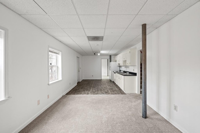 kitchen with a drop ceiling, carpet flooring, white cabinets, open floor plan, and freestanding refrigerator