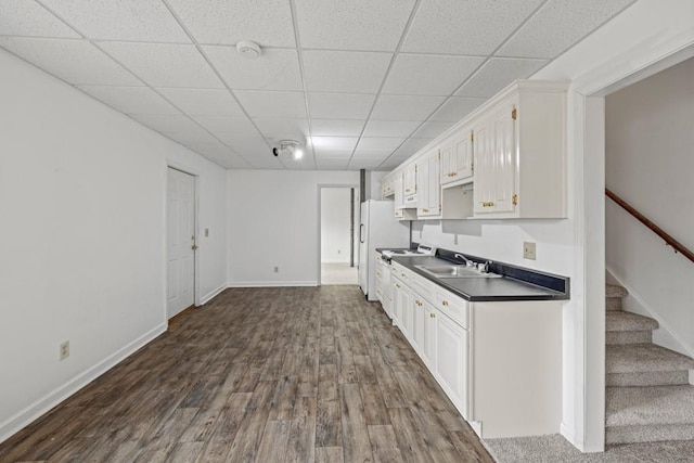 kitchen featuring white appliances, a sink, white cabinets, dark wood-style floors, and dark countertops