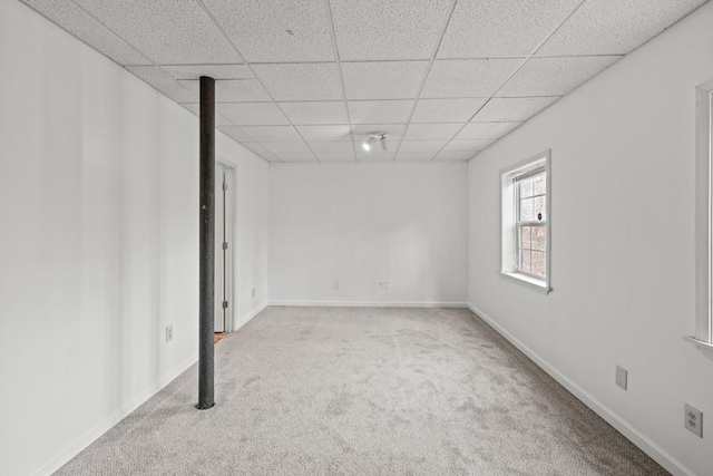 interior space featuring a paneled ceiling and baseboards