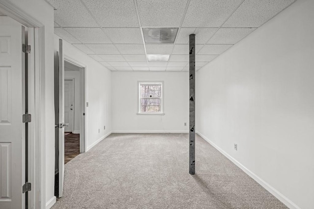 basement with a paneled ceiling, carpet, and baseboards