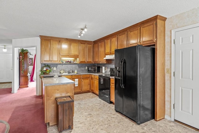 kitchen with a textured ceiling, under cabinet range hood, a sink, light countertops, and black appliances