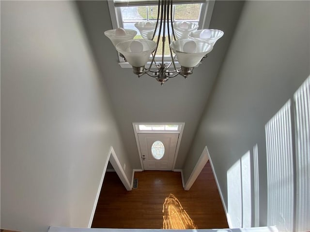 entryway with an inviting chandelier, dark wood-type flooring, and a towering ceiling