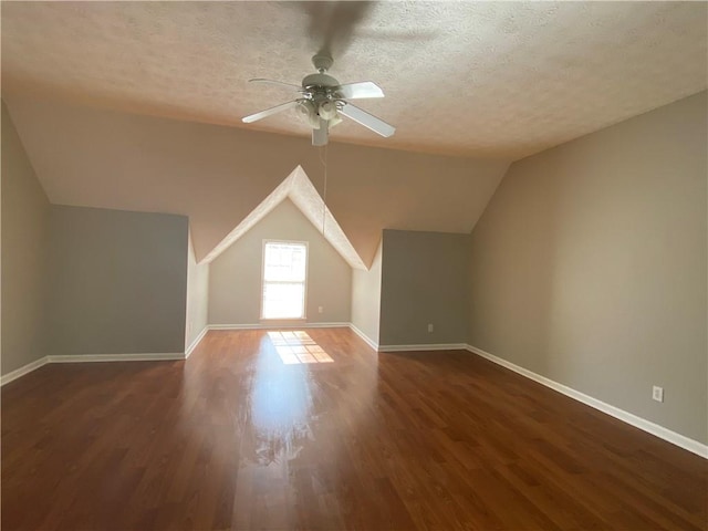 bonus room with dark wood-type flooring, vaulted ceiling, a textured ceiling, and ceiling fan