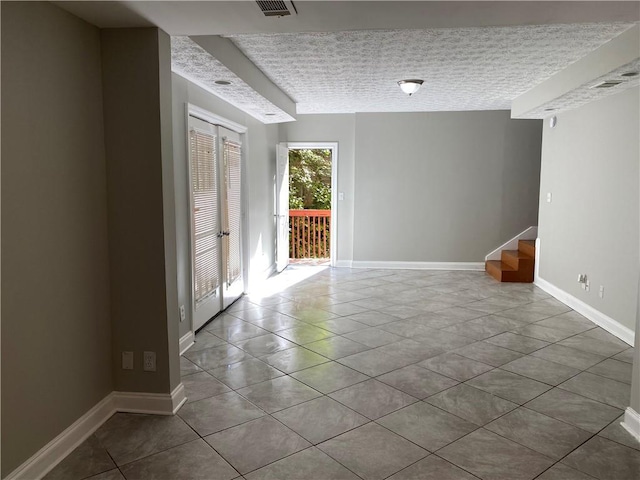 empty room featuring a textured ceiling and tile patterned flooring