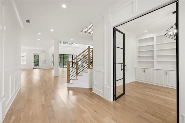interior space with visible vents, stairs, light wood-type flooring, recessed lighting, and a decorative wall