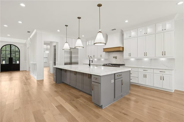 kitchen with custom exhaust hood, gray cabinets, white cabinetry, tasteful backsplash, and stainless steel built in refrigerator