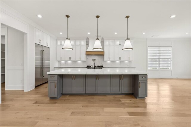 kitchen featuring custom exhaust hood, white cabinets, light countertops, and stainless steel built in refrigerator