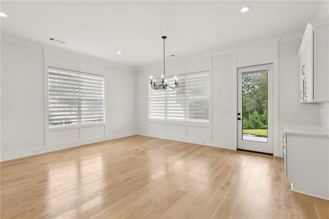 unfurnished dining area with visible vents, light wood finished floors, recessed lighting, crown molding, and a notable chandelier