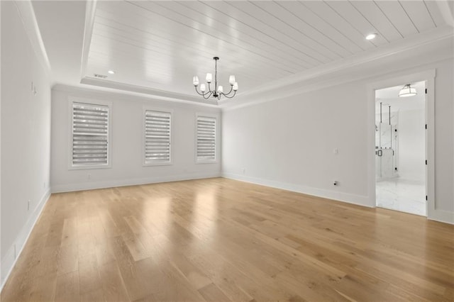empty room with a raised ceiling, wood ceiling, light wood finished floors, and a chandelier