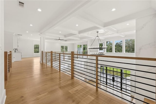 hallway featuring visible vents, beam ceiling, wood finished floors, a notable chandelier, and coffered ceiling