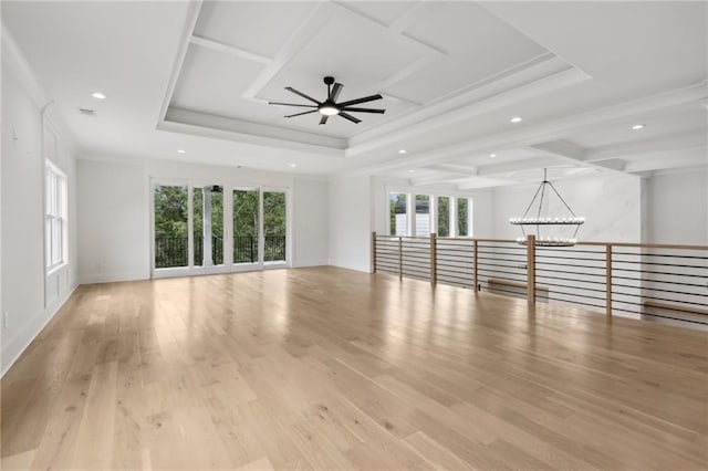 unfurnished living room featuring light wood finished floors, ornamental molding, recessed lighting, ceiling fan with notable chandelier, and a raised ceiling