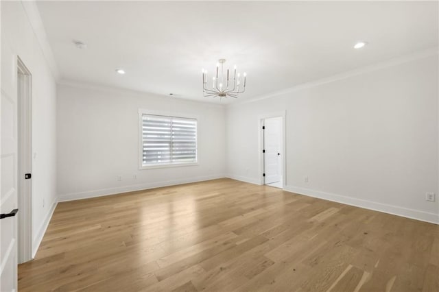 empty room with an inviting chandelier, light wood-style flooring, baseboards, and ornamental molding