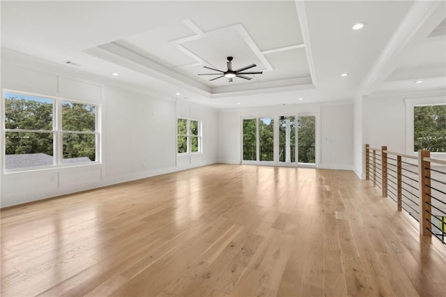 unfurnished living room featuring light wood finished floors, crown molding, baseboards, a raised ceiling, and a ceiling fan