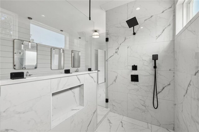 bathroom featuring a marble finish shower, marble finish floor, tile walls, and double vanity