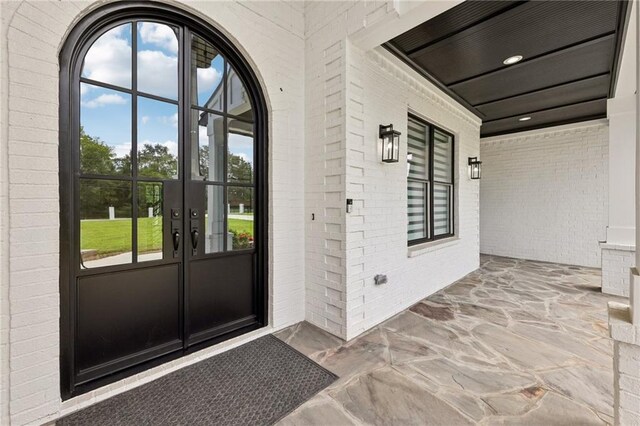 property entrance featuring french doors and brick siding