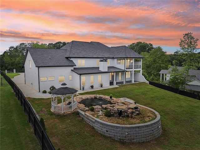 back of property with a gazebo, a yard, a fenced backyard, and roof with shingles