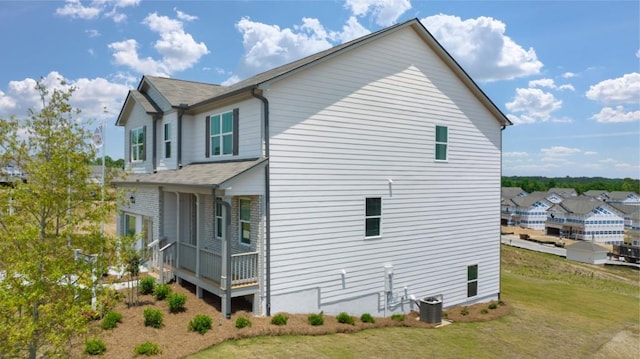 view of side of home featuring a yard, central AC unit, and a porch