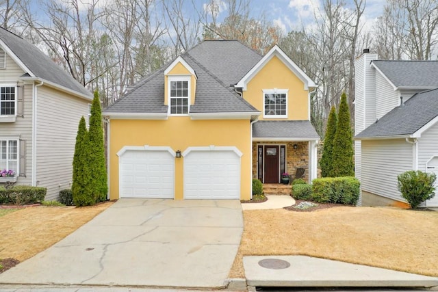 traditional home featuring an attached garage, roof with shingles, concrete driveway, and stucco siding