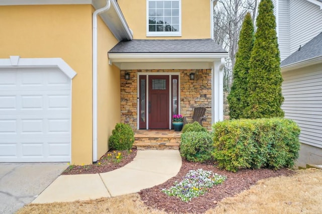 entrance to property featuring a garage, stone siding, a shingled roof, and stucco siding