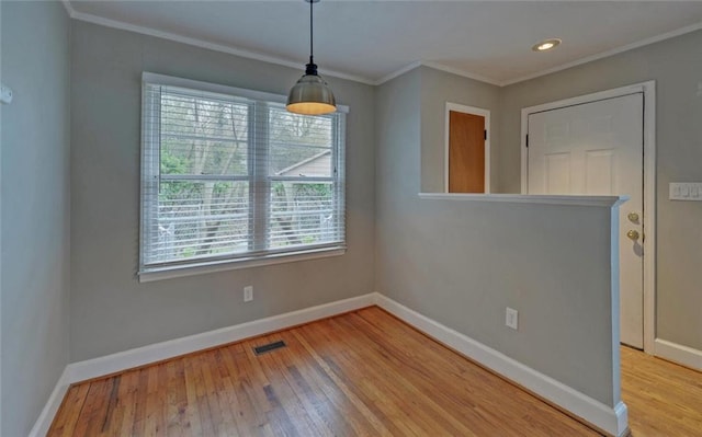 unfurnished dining area featuring baseboards, visible vents, crown molding, and wood finished floors