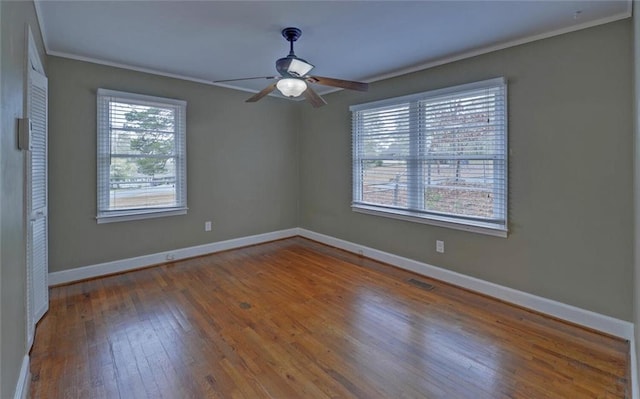empty room with baseboards, crown molding, ceiling fan, and hardwood / wood-style flooring