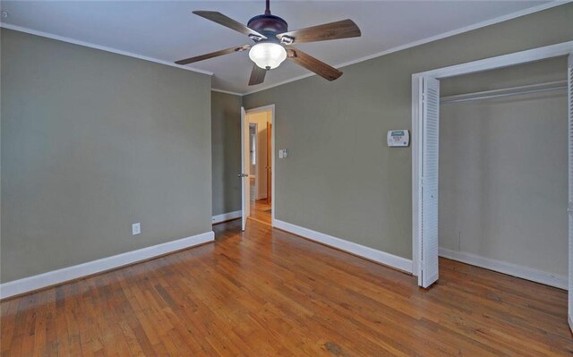 unfurnished bedroom featuring a closet, baseboards, ornamental molding, a ceiling fan, and wood-type flooring