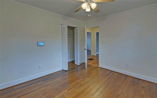 unfurnished bedroom with baseboards, a closet, crown molding, and hardwood / wood-style flooring