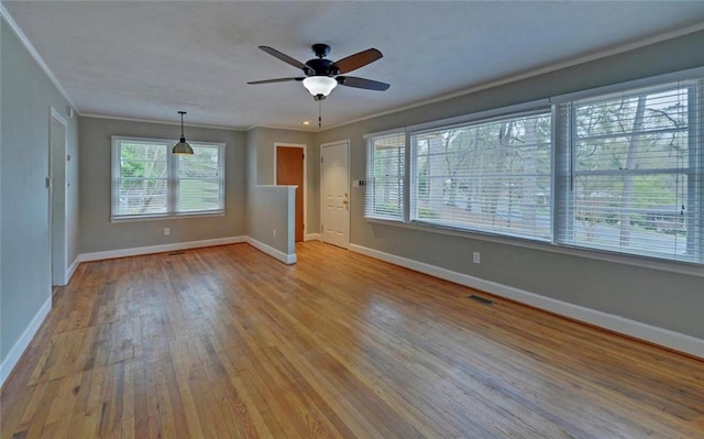spare room featuring visible vents, crown molding, baseboards, ceiling fan, and wood-type flooring