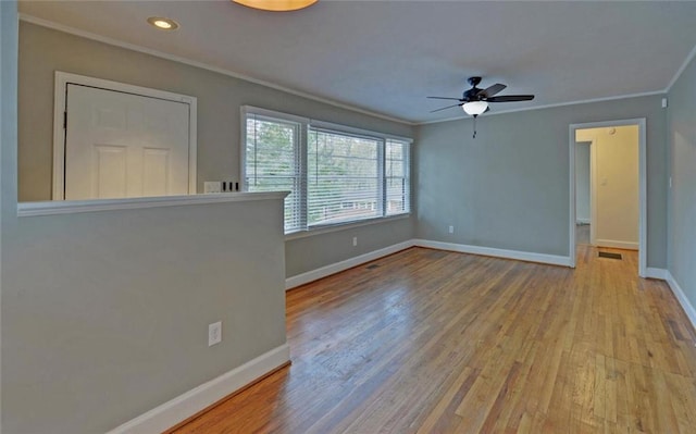 unfurnished living room featuring visible vents, baseboards, ornamental molding, wood finished floors, and a ceiling fan
