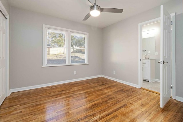 unfurnished bedroom with a sink, a closet, light wood finished floors, ceiling fan, and baseboards